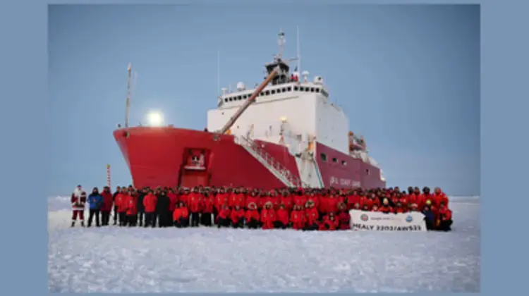 USCGC Healy at the North Pole with crew in front on ship on the ice