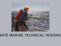 Person leaning on a ship's rail wearing a life jacket and hard hat with the background of a gray sea